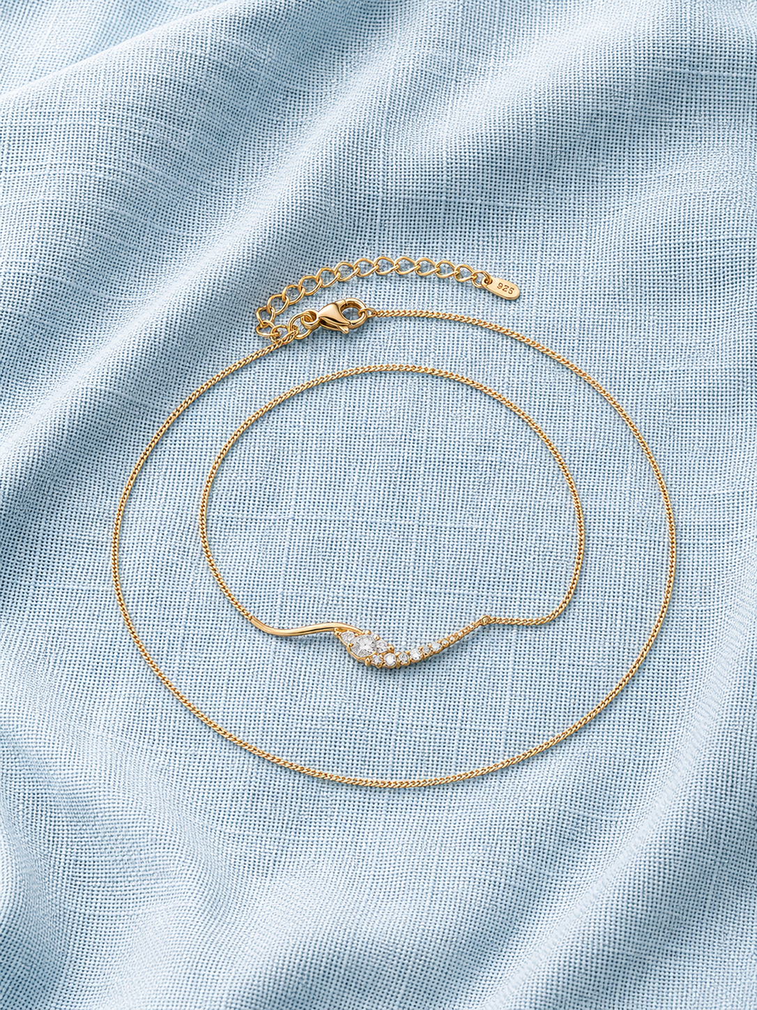 Dainty Curved Crystal Bar Necklace on blue linen fabric